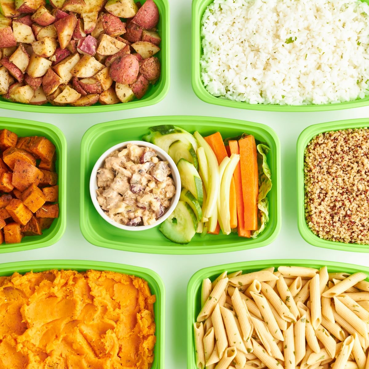 Viandas variadas con vegetales y proteinas en recipientes verdes
